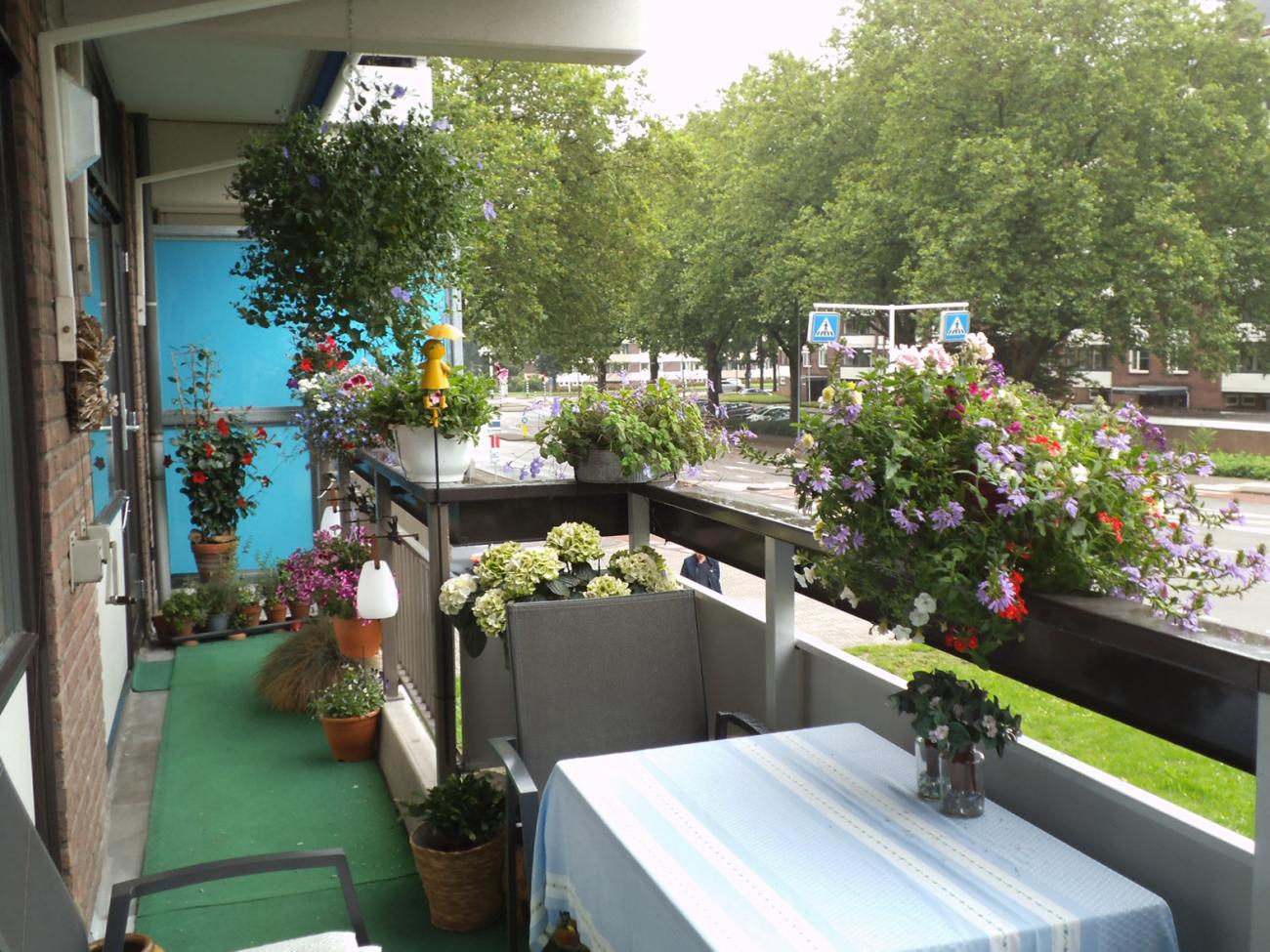 foto van balkon met daarop een tafel en allemaal bloemen