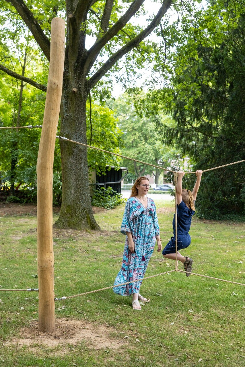 moeder staat bij spelend kind in park