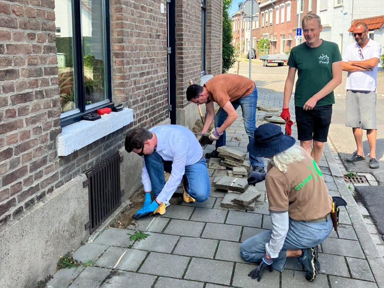 groep mensen die tegels uit de stoep halen