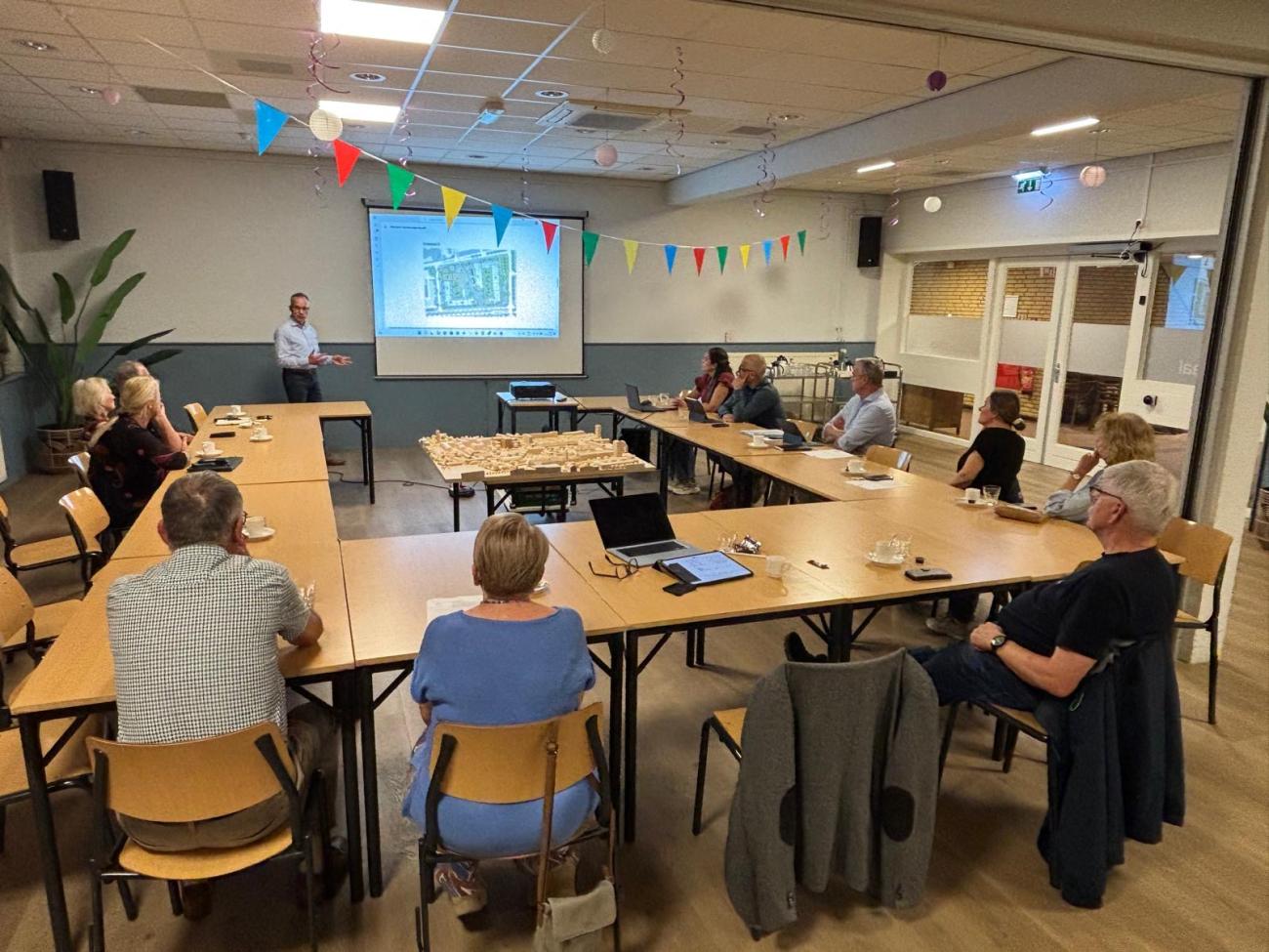 Groep mensen aan tafels voor een scherm