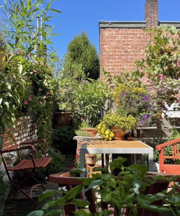 foto van balkon met tafel en groene planten en een boom en stoelen