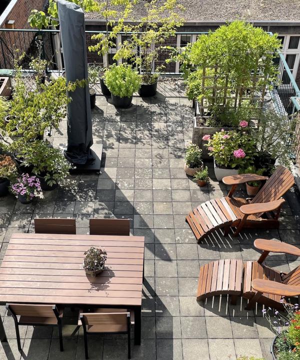 balkon met tafel en stoelen en grijze tegels en groene planten
