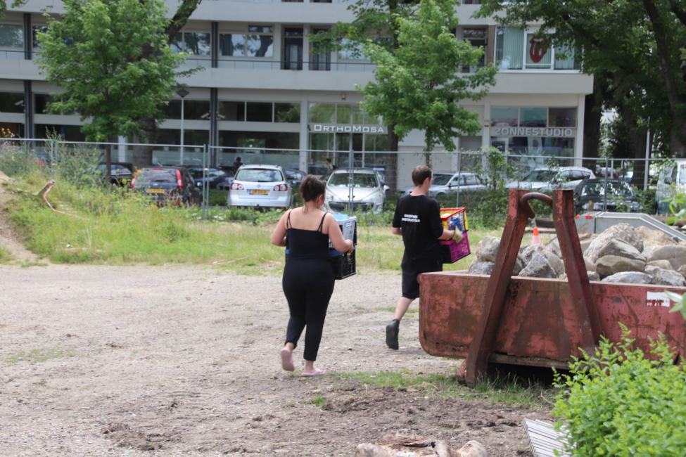 Afbeelding mensen die puin naar rode container brengen