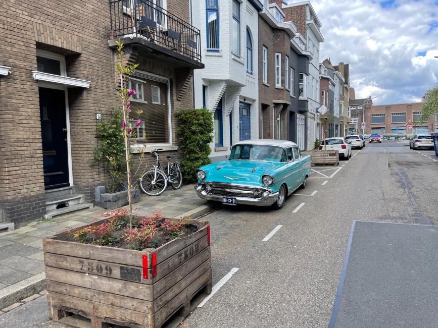 Een straat met auto's en grote bloembakken
