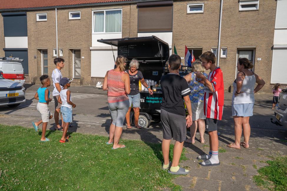 Bewoners halen een ijsje bij een ijskar in een woonstraat in Pottenberg.