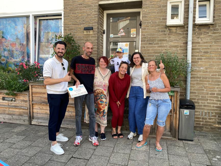 Groep bewoners poseert voor een woning na de uitreiking van de prijs voor de Mooiste Straat van Pottenberg.